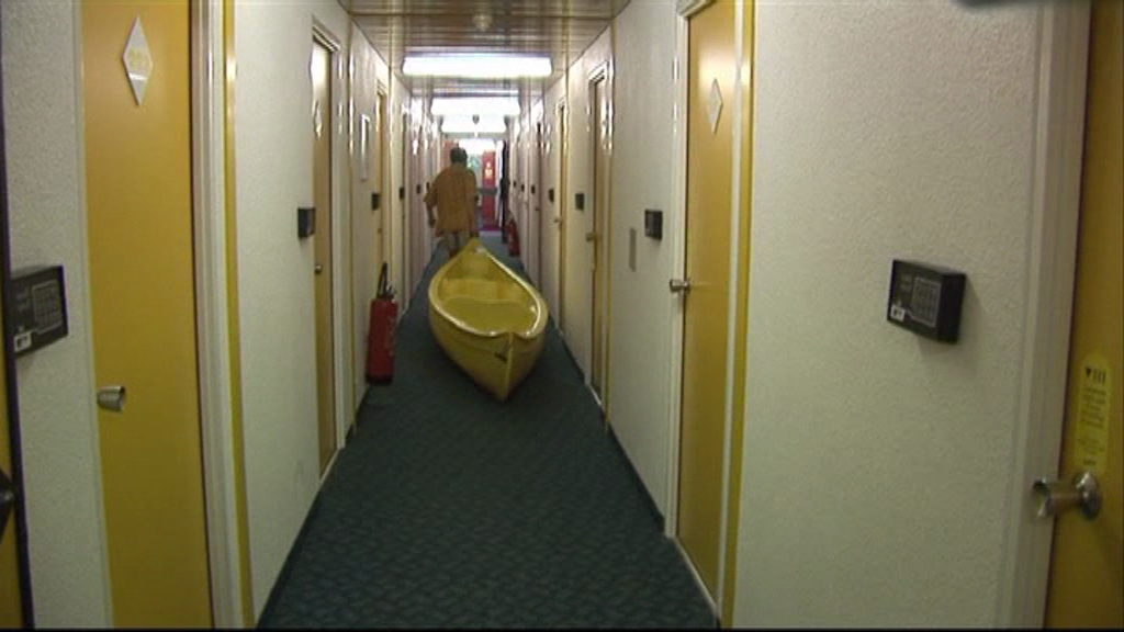 Homme tirant une barque jaune dans un couloir