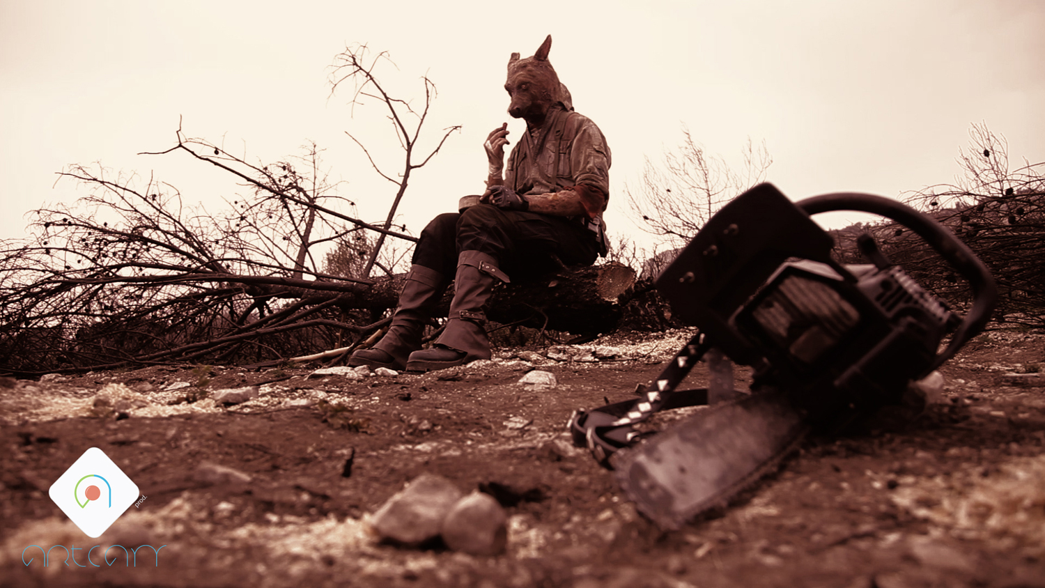 Un homme kangourou est assis sur une pierre, dans la garrigue, et devant lui, au sol, se trouve une tronçonneuse