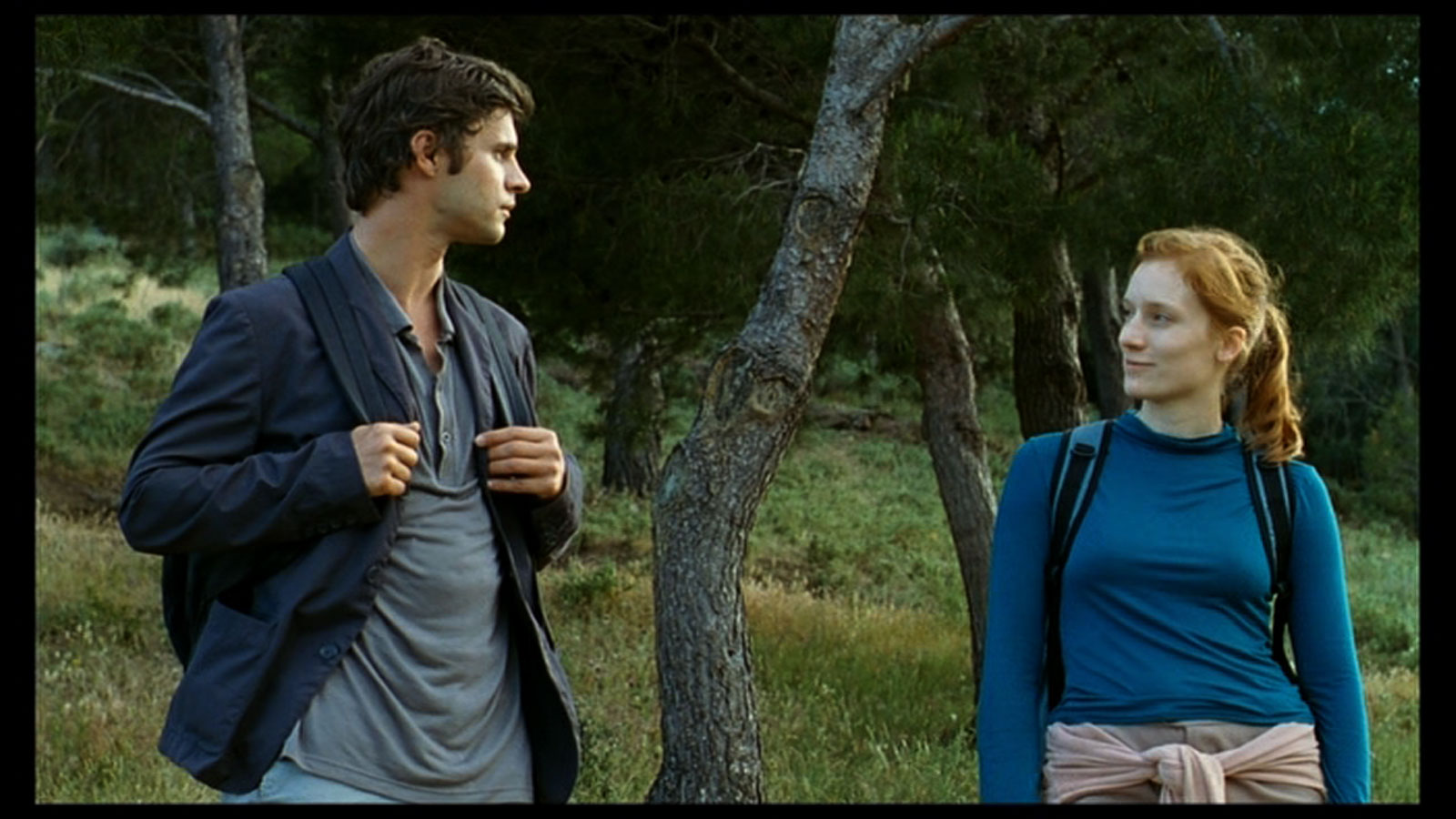 //www.occitanie-films.netUn homme et une femme se baladent, équipés de sacs à dos, dans une forêt