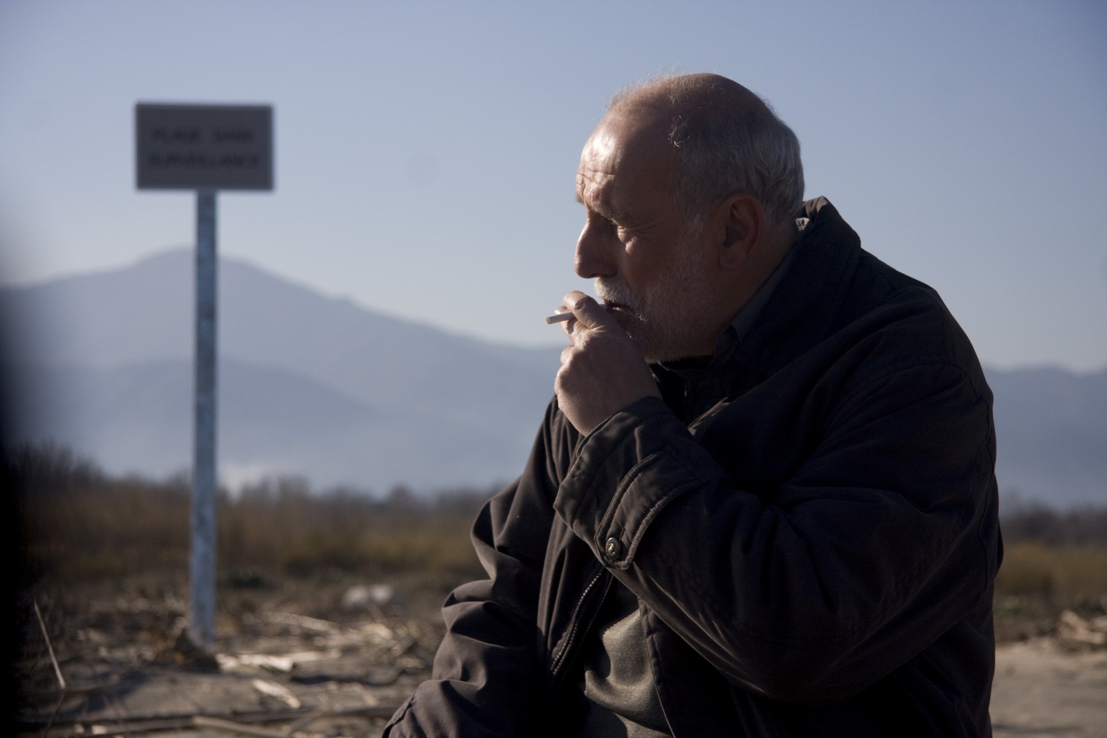 //www.occitanie-films.netUn homme d'environ quatre-vingts ans fume une cigarette au bord d'une route