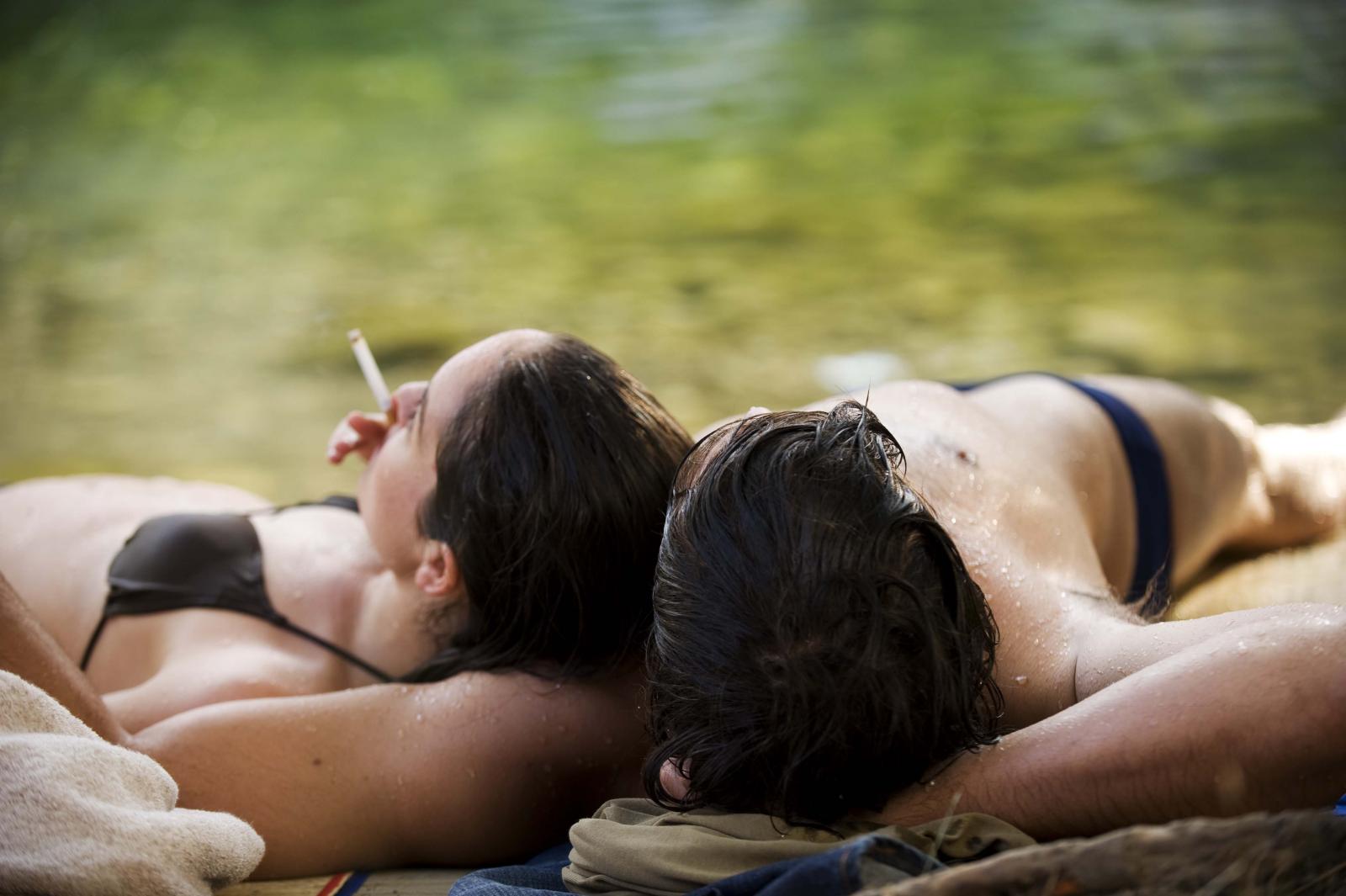 Jeune couple allongé au bord d'une rivière en maillots de bain
