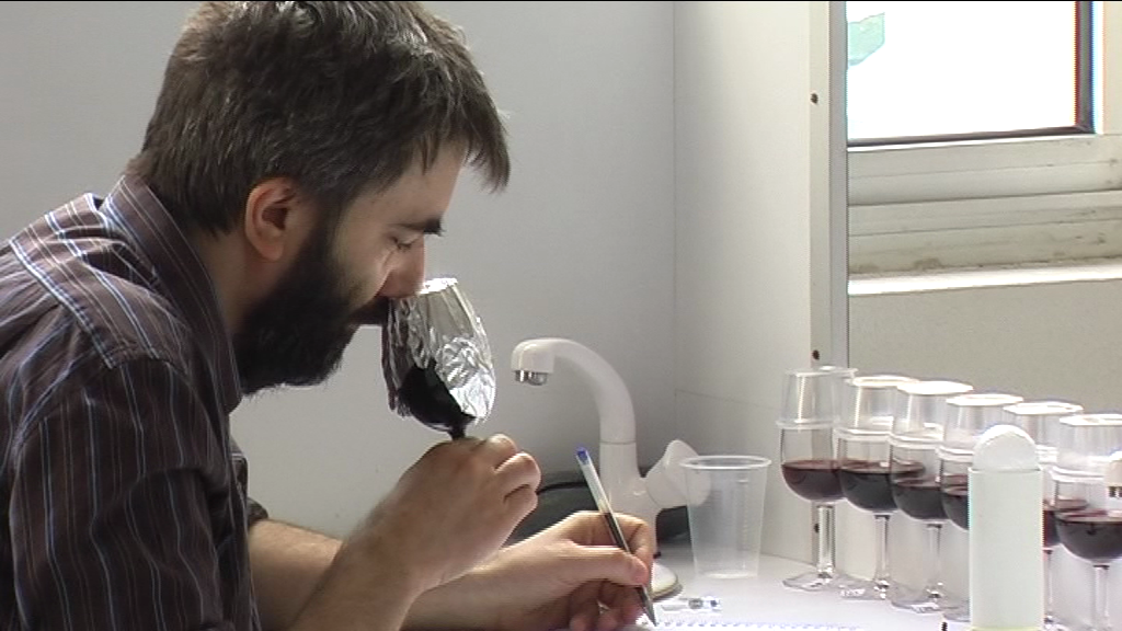 Homme sentant un verre de vin noir recouvert d'aluminium