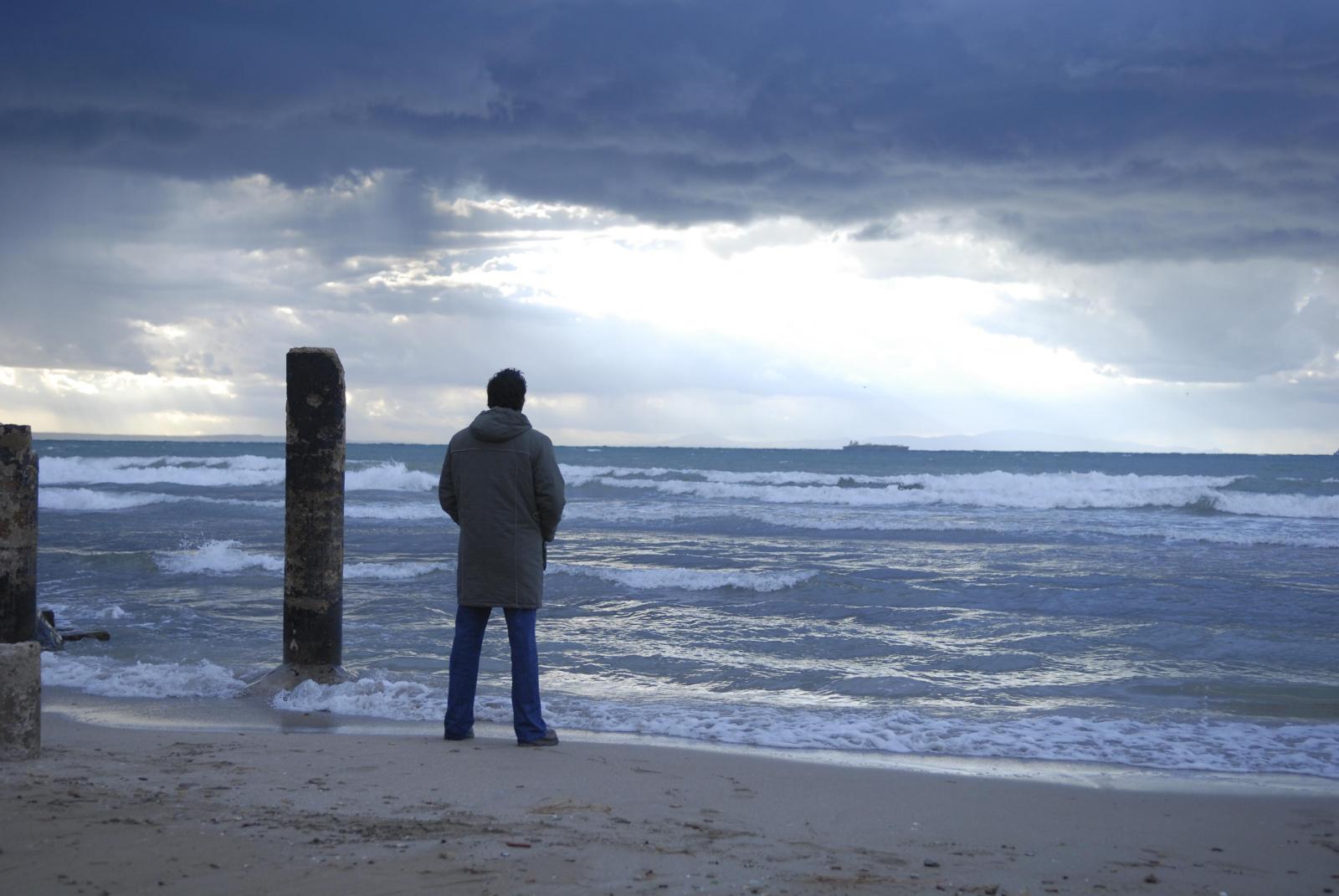 Un homme de dos debout face à la mer