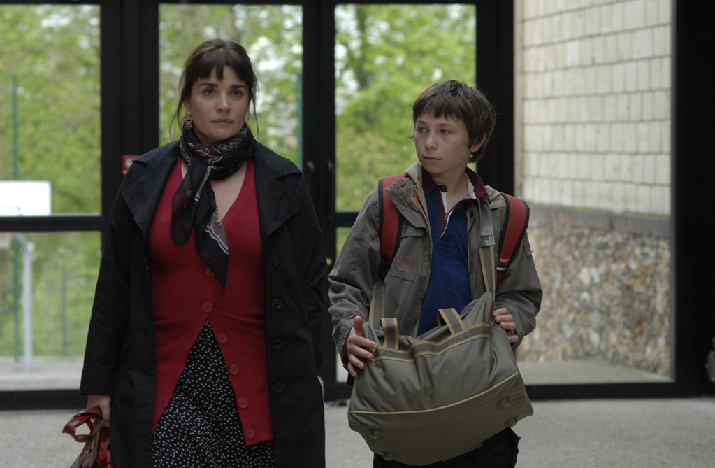 //www.occitanie-films.netUne femme et un jeune adolescent marchent dans le hall d'entrée d'un immeuble