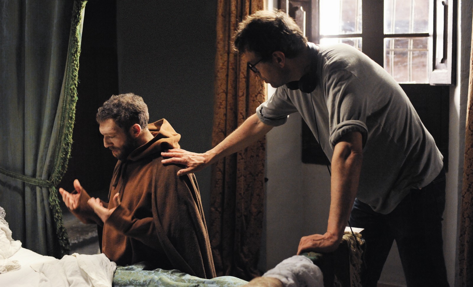 //www.occitanie-films.netMoine (Vincent Cassel) agenouillé au pied d'un lit, priant. Un homme lui pose la main sur l'épaule