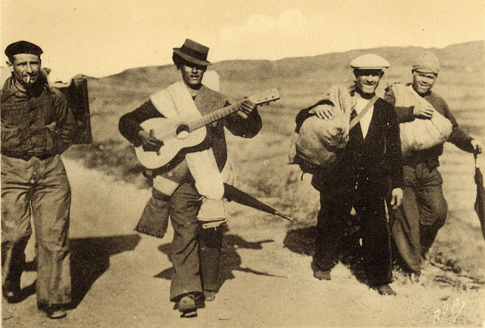 Photo sépia des années 1930 d'un groupe de paysans espagnols marchant tout en jouant de la guitare