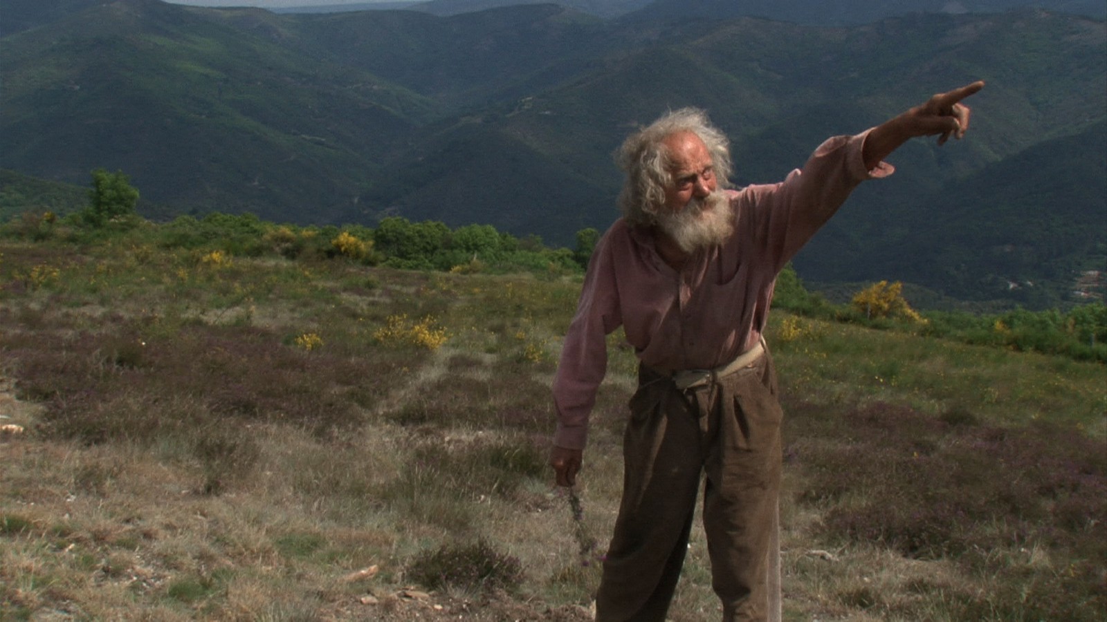Diourka pointe du doigt un point au loin, dans un champ en plein coeur des montagnes